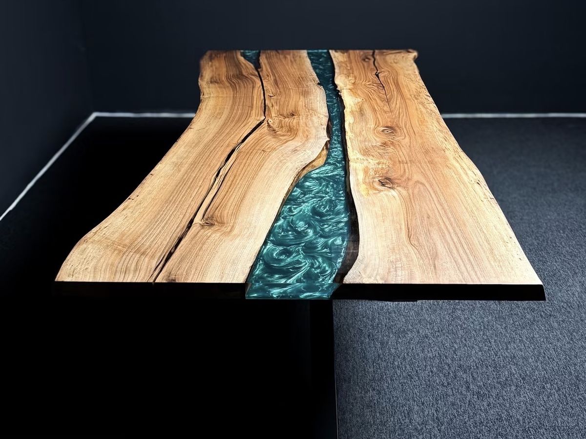 Long live-edge wood dining table with a swirling pearlescent teal resin river on black steel legs