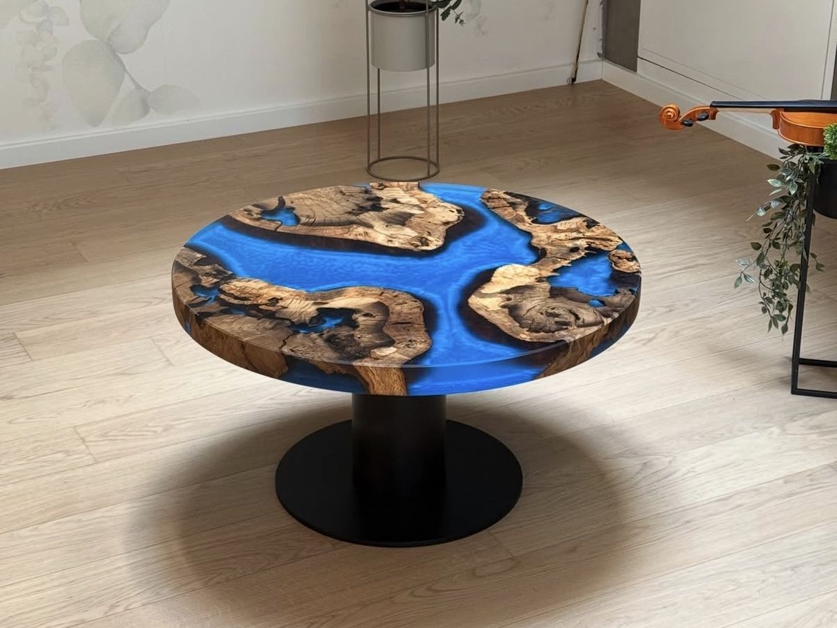 Round coffee table of burl wood islands set in glowing blue resin on a black steel pedestal