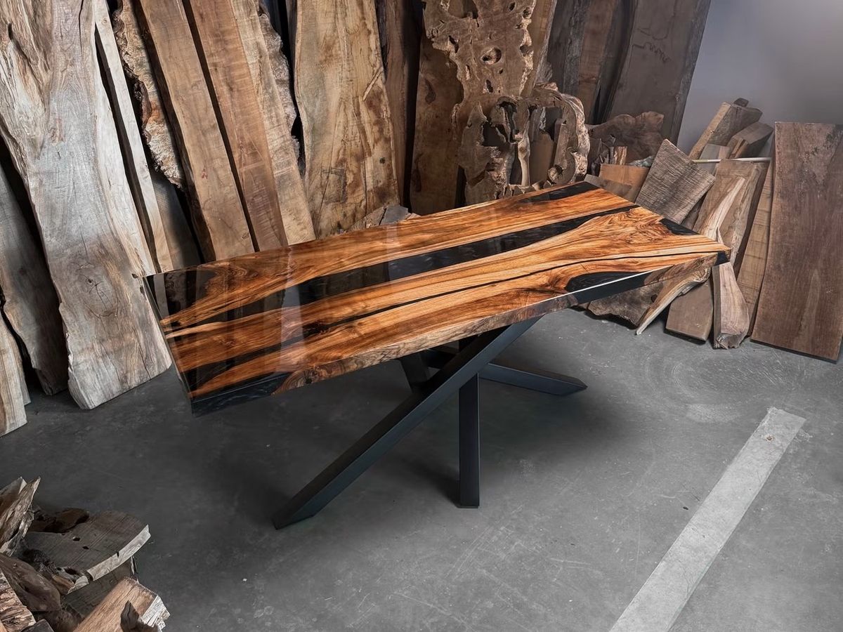 Rectangular wood table with black resin rivers on a crossed steel base in the workshop